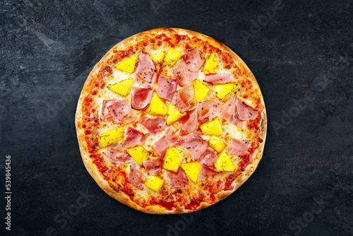 Traditionelle italienische Pizza Hawaii mit Schinken, Ananas und Mozzarella serviert als Draufsicht auf einem alten rustikalen Board mit Textfreiraum 