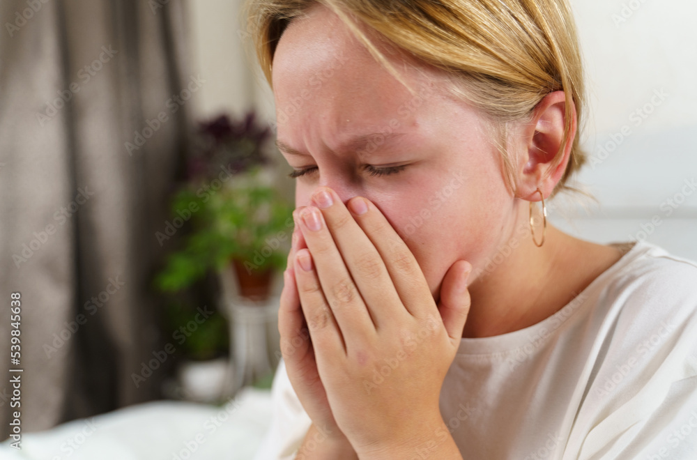 The sick girl coughs heavily, covering her mouth with her hands. The sick girl coughs heavily, covering her mouth with her hands.
