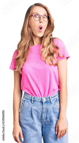 Young beautiful caucasian woman with blond hair wearing casual clothes and glasses afraid and shocked with surprise expression, fear and excited face. © Krakenimages.com