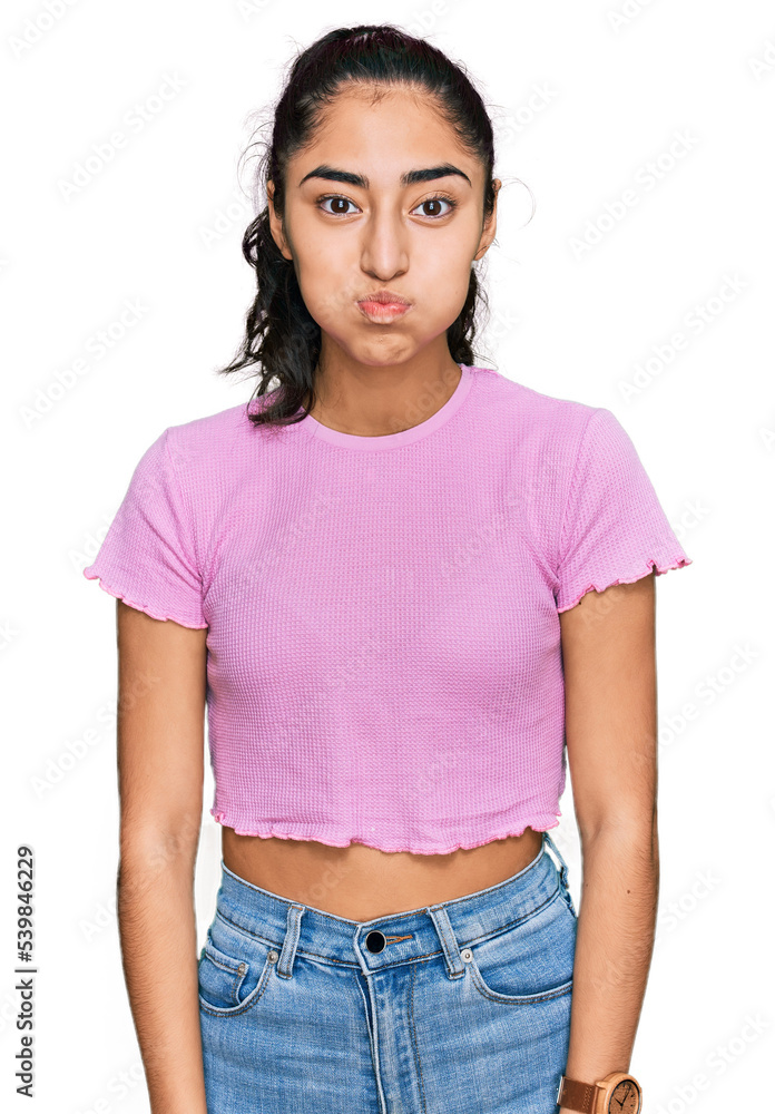 Obraz premium Hispanic teenager girl with dental braces wearing casual clothes puffing cheeks with funny face. mouth inflated with air, crazy expression.