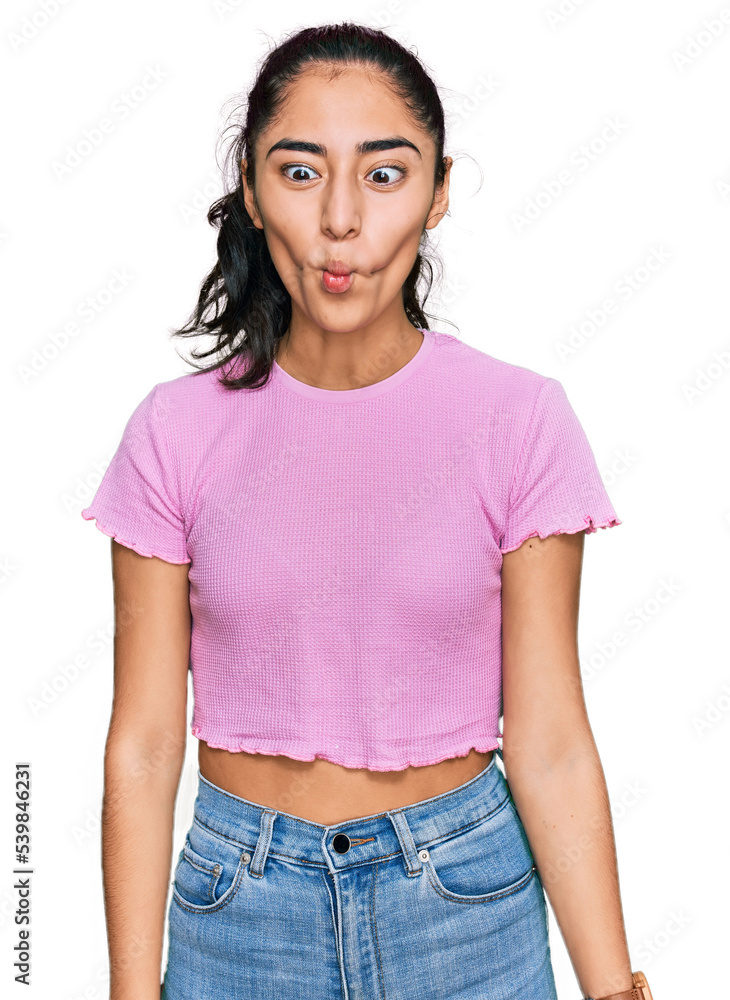 Hispanic teenager girl with dental braces wearing casual clothes making fish face with lips, crazy and comical gesture. funny expression. Hispanic teenager girl with dental braces wearing casual clothes making fish face with lips, crazy and comical gesture. funny expression.