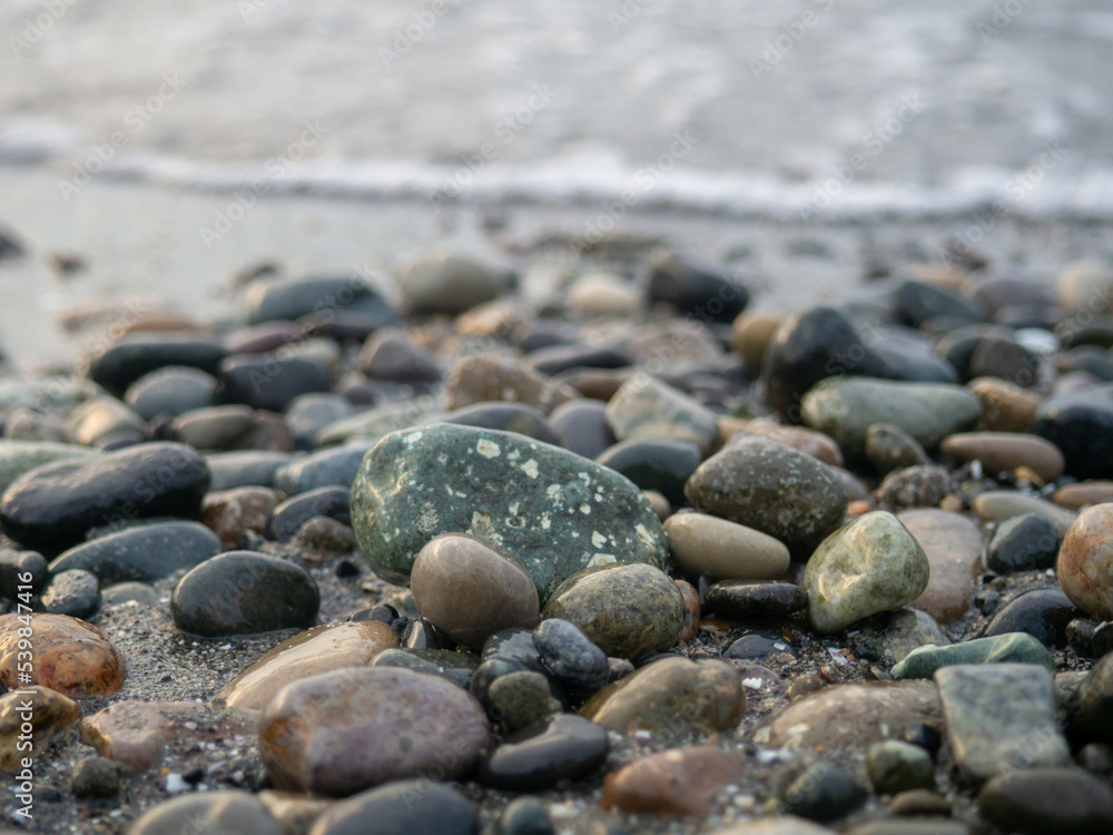 Pebbles on the seashore close-up. Rocky beach. Stones close-up with bokeh. Gray natural background. The concept of rest on the seashore. The Velvet season. Waves and wet pebbles Pebbles on the seashore close-up. Rocky beach. Stones close-up with bokeh. Gray natural background. The concept of rest on the seashore. The Velvet season. Waves and wet pebbles