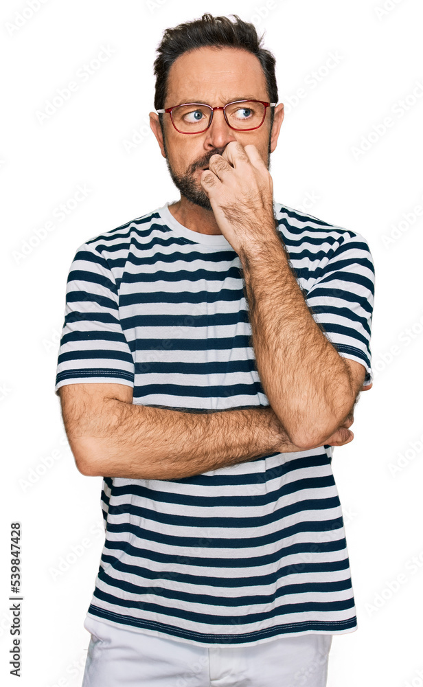 Middle age man wearing casual clothes and glasses looking stressed and nervous with hands on mouth biting nails. anxiety problem. Middle age man wearing casual clothes and glasses looking stressed and nervous with hands on mouth biting nails. anxiety problem.