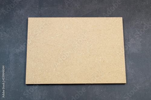 Board of raw mdf, brown color, on a dark background.