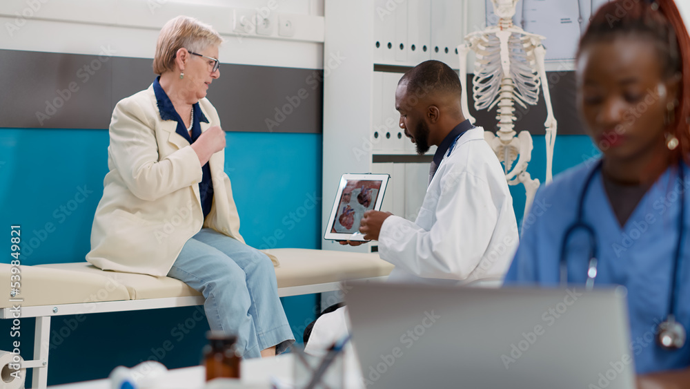 Obraz premium Cardiology medic showing cardiogram diagnosis on digital tablet to sick woman with cardiac disease. Looking at cardiovascular ecg and heart organ on display to find healthcare treatment.