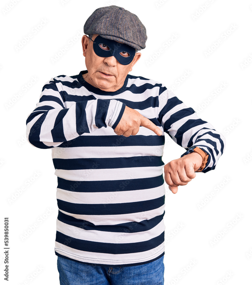 Senior handsome man wearing burglar mask and t-shirt in hurry pointing to watch time, impatience, upset and angry for deadline delay Senior handsome man wearing burglar mask and t-shirt in hurry pointing to watch time, impatience, upset and angry for deadline delay