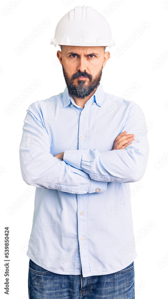 Young handsome man wearing architect hardhat skeptic and nervous, disapproving expression on face with crossed arms. negative person. Young handsome man wearing architect hardhat skeptic and nervous, disapproving expression on face with crossed arms. negative person.