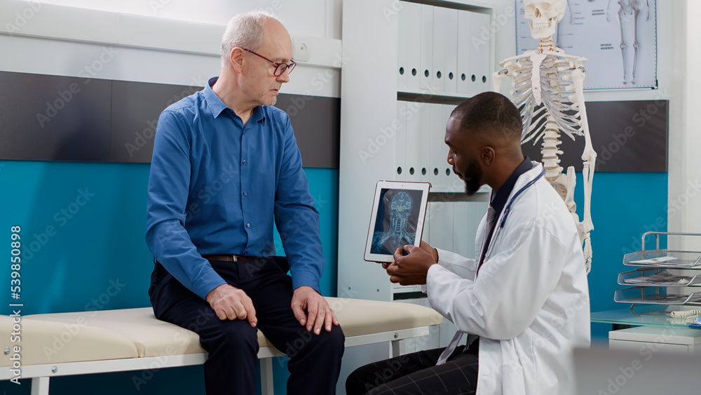 African american doctor analyzing radiography results to old man, examining bones diagnosis to give prescription treatment. Physician looking at x ray scan on digital tablet, checkup appointment.