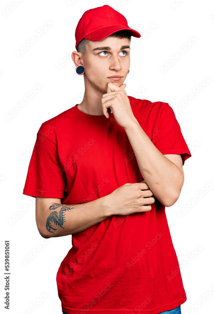 Young caucasian boy with ears dilation wearing delivery uniform and cap serious face thinking about question with hand on chin, thoughtful about confusing idea Young caucasian boy with ears dilation wearing delivery uniform and cap serious face thinking about question with hand on chin, thoughtful about confusing idea