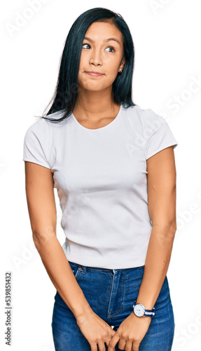 Beautiful hispanic woman wearing casual white tshirt smiling looking to the side and staring away thinking.