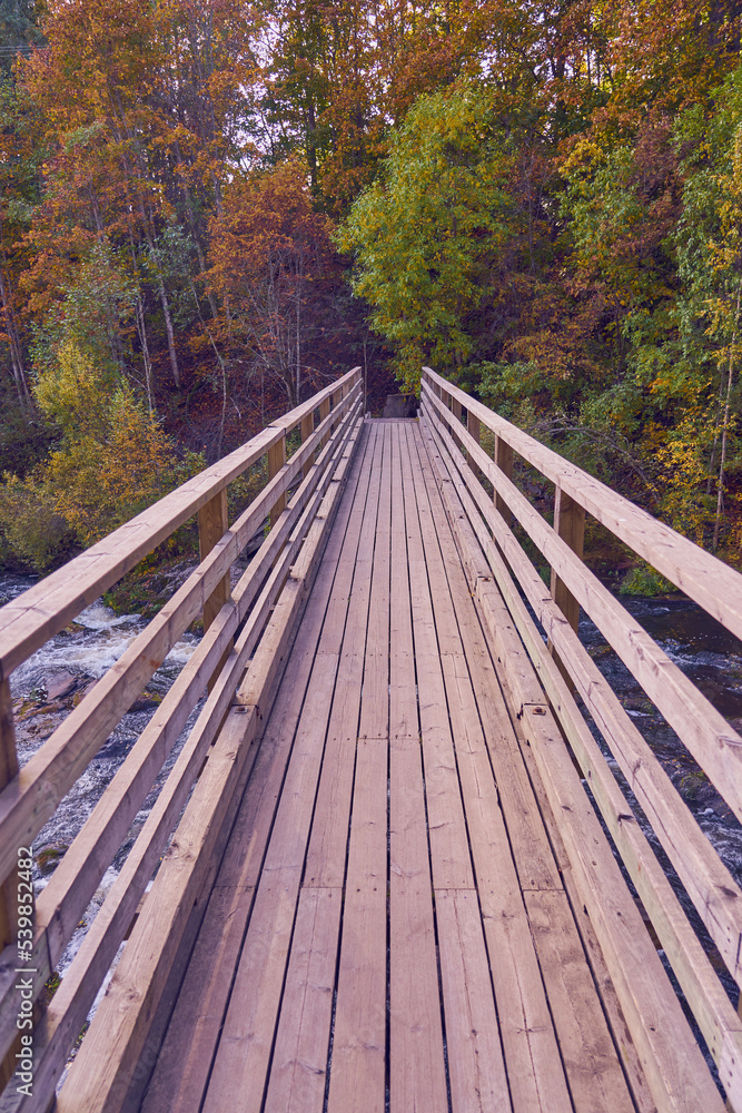 Wooden bridge over a mountain river in the autumn forest. Wooden bridge over a mountain river in the autumn forest.