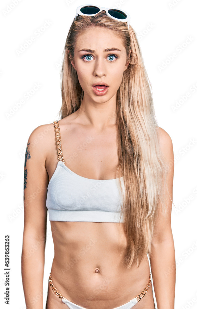 Obraz premium Beautiful young blonde woman wearing bikini afraid and shocked with surprise expression, fear and excited face.