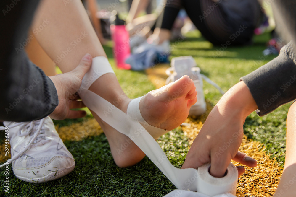 Teenage girl high school cheerleading team taping wrists with tape at