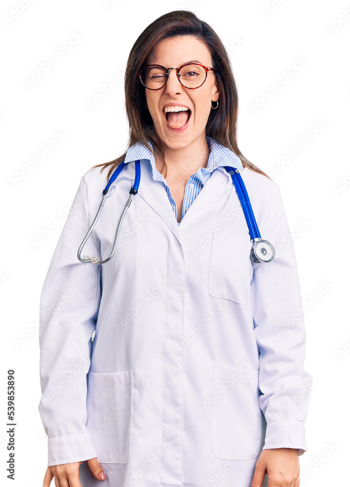 Young beautiful woman wearing doctor stethoscope and glasses winking looking at the camera with sexy expression, cheerful and happy face. Young beautiful woman wearing doctor stethoscope and glasses winking looking at the camera with sexy expression, cheerful and happy face.