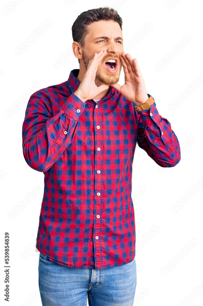 Handsome young man with bear wearing casual shirt shouting angry out loud with hands over mouth Handsome young man with bear wearing casual shirt shouting angry out loud with hands over mouth