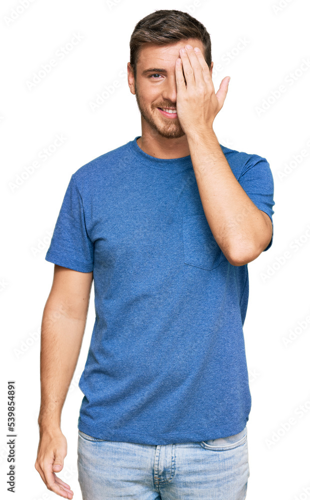 Handsome caucasian man wearing casual clothes covering one eye with hand, confident smile on face and surprise emotion. Handsome caucasian man wearing casual clothes covering one eye with hand, confident smile on face and surprise emotion.
