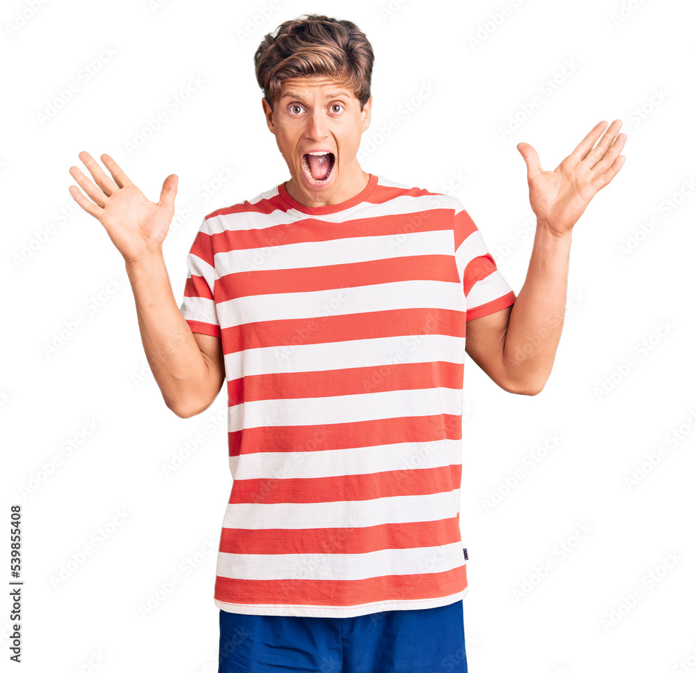 Naklejka premium Young handsome man wearing casual clothes celebrating crazy and amazed for success with arms raised and open eyes screaming excited. winner concept