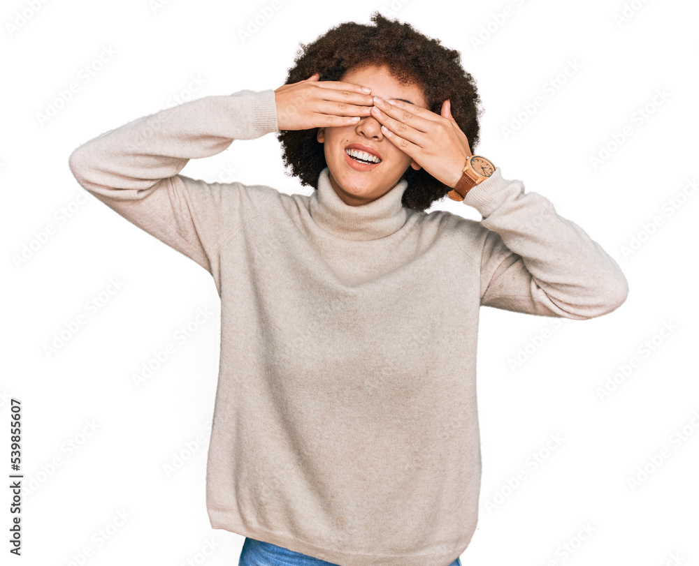 Young hispanic girl wearing wool winter sweater covering eyes with hands smiling cheerful and funny. blind concept. Young hispanic girl wearing wool winter sweater covering eyes with hands smiling cheerful and funny. blind concept.