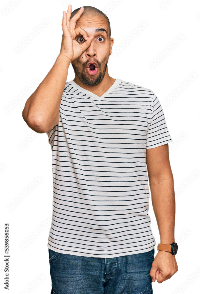 Hispanic adult man wearing casual clothes doing ok gesture shocked with surprised face, eye looking through fingers. unbelieving expression. Hispanic adult man wearing casual clothes doing ok gesture shocked with surprised face, eye looking through fingers. unbelieving expression.