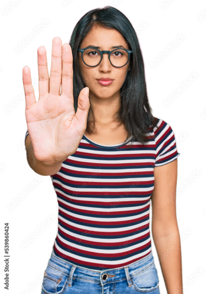 Beautiful asian young woman wearing casual clothes and glasses doing stop sing with palm of the hand. warning expression with negative and serious gesture on the face. Beautiful asian young woman wearing casual clothes and glasses doing stop sing with palm of the hand. warning expression with negative and serious gesture on the face.