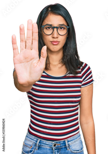 Beautiful asian young woman wearing casual clothes and glasses doing stop sing with palm of the hand. warning expression with negative and serious gesture on the face.