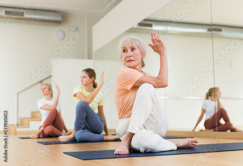 Portrait of positive mature woman pensioner training stretching workout in modern studio