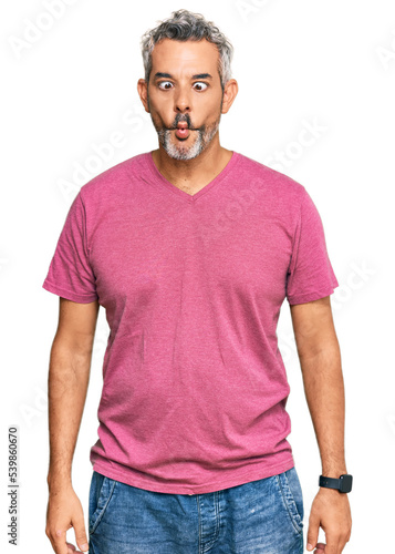 Middle age grey-haired man wearing casual clothes making fish face with lips  crazy and comical gesture. funny expression.