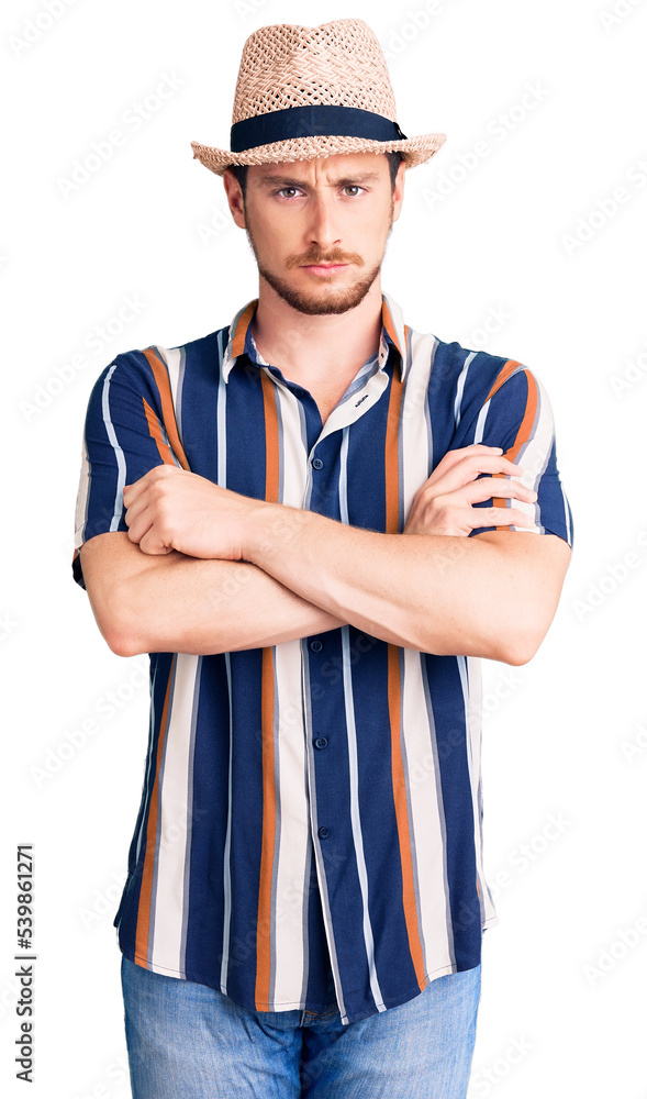 Young handsome caucasian man wearing summer hat skeptic and nervous, disapproving expression on face with crossed arms. negative person. Young handsome caucasian man wearing summer hat skeptic and nervous, disapproving expression on face with crossed arms. negative person.