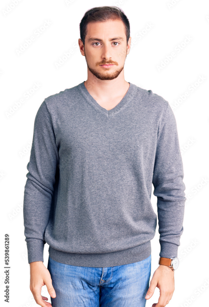 Young handsome caucasian man wearing casual winter sweater with serious expression on face. simple and natural looking at the camera. Young handsome caucasian man wearing casual winter sweater with serious expression on face. simple and natural looking at the camera.
