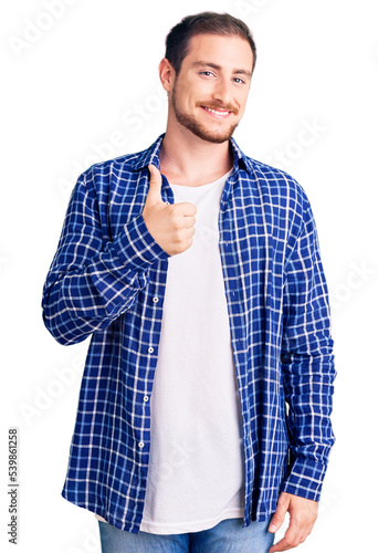 Young handsome caucasian man wearing casual clothes doing happy thumbs up gesture with hand. approving expression looking at the camera showing success.