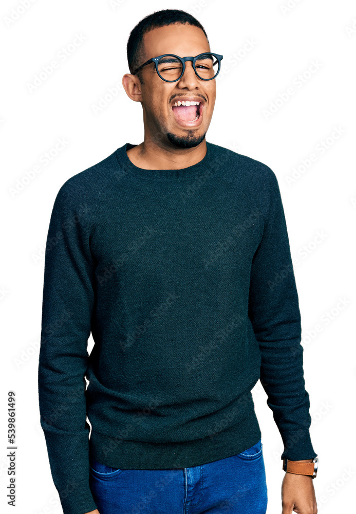 Young african american man wearing casual clothes and glasses winking looking at the camera with sexy expression, cheerful and happy face. Young african american man wearing casual clothes and glasses winking looking at the camera with sexy expression, cheerful and happy face.