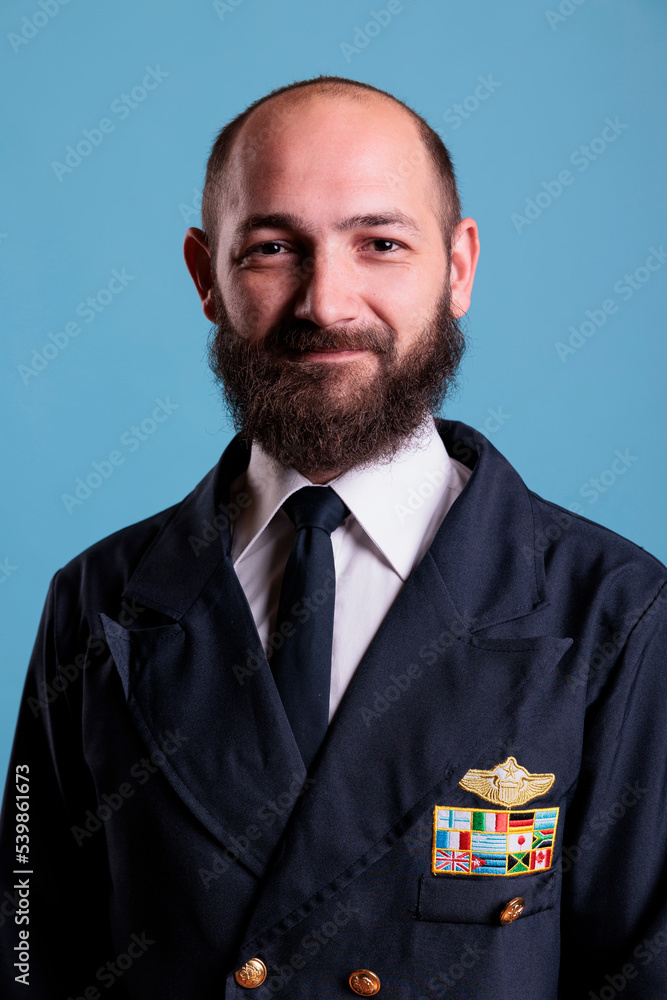 Smiling airplane pilot wearing uniform medium close up portrait, plane captain looking at camera. Middle age aviator with civil badge on professional suit, aircrew member Smiling airplane pilot wearing uniform medium close up portrait, plane captain looking at camera. Middle age aviator with civil badge on professional suit, aircrew member