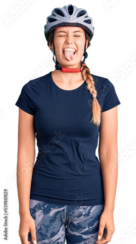Beautiful caucasian woman wearing bike helmet sticking tongue out happy with funny expression. emotion concept.