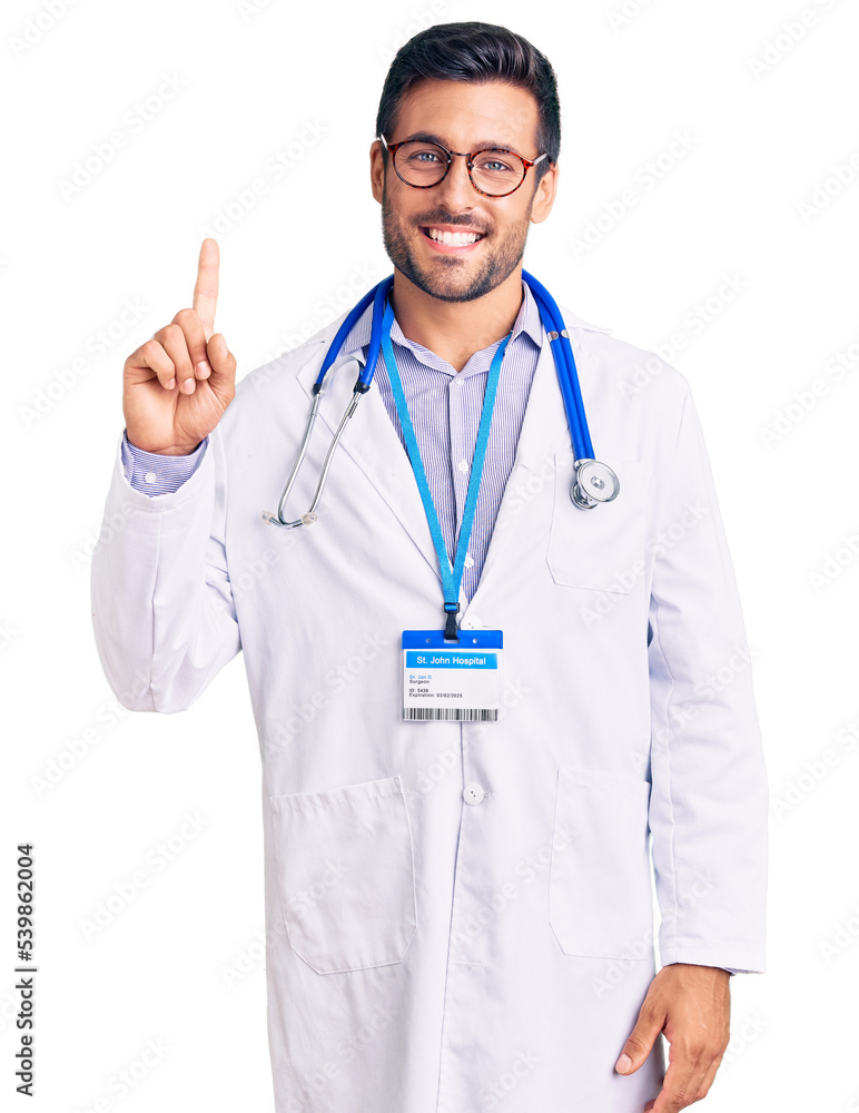 Young hispanic man wearing doctor uniform and stethoscope showing and pointing up with finger number one while smiling confident and happy. Young hispanic man wearing doctor uniform and stethoscope showing and pointing up with finger number one while smiling confident and happy.