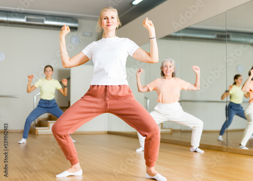 Woman dancing modern dance with other women during group training