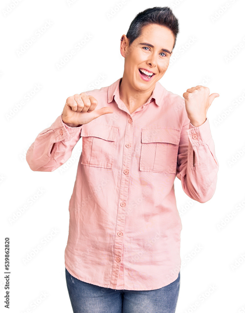 Young woman with short hair wearing casual clothes pointing to the back behind with hand and thumbs up, smiling confident