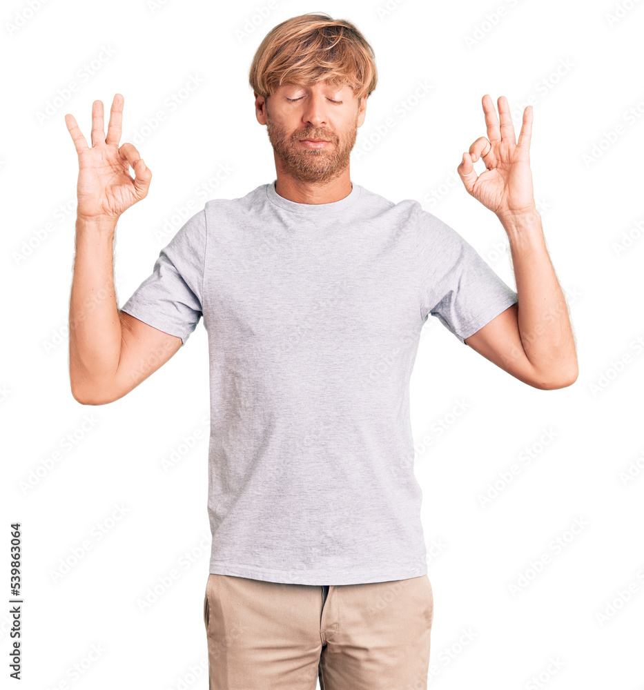 Fototapeta premium Handsome caucasian man with beard wearing casual tshirt relax and smiling with eyes closed doing meditation gesture with fingers. yoga concept.