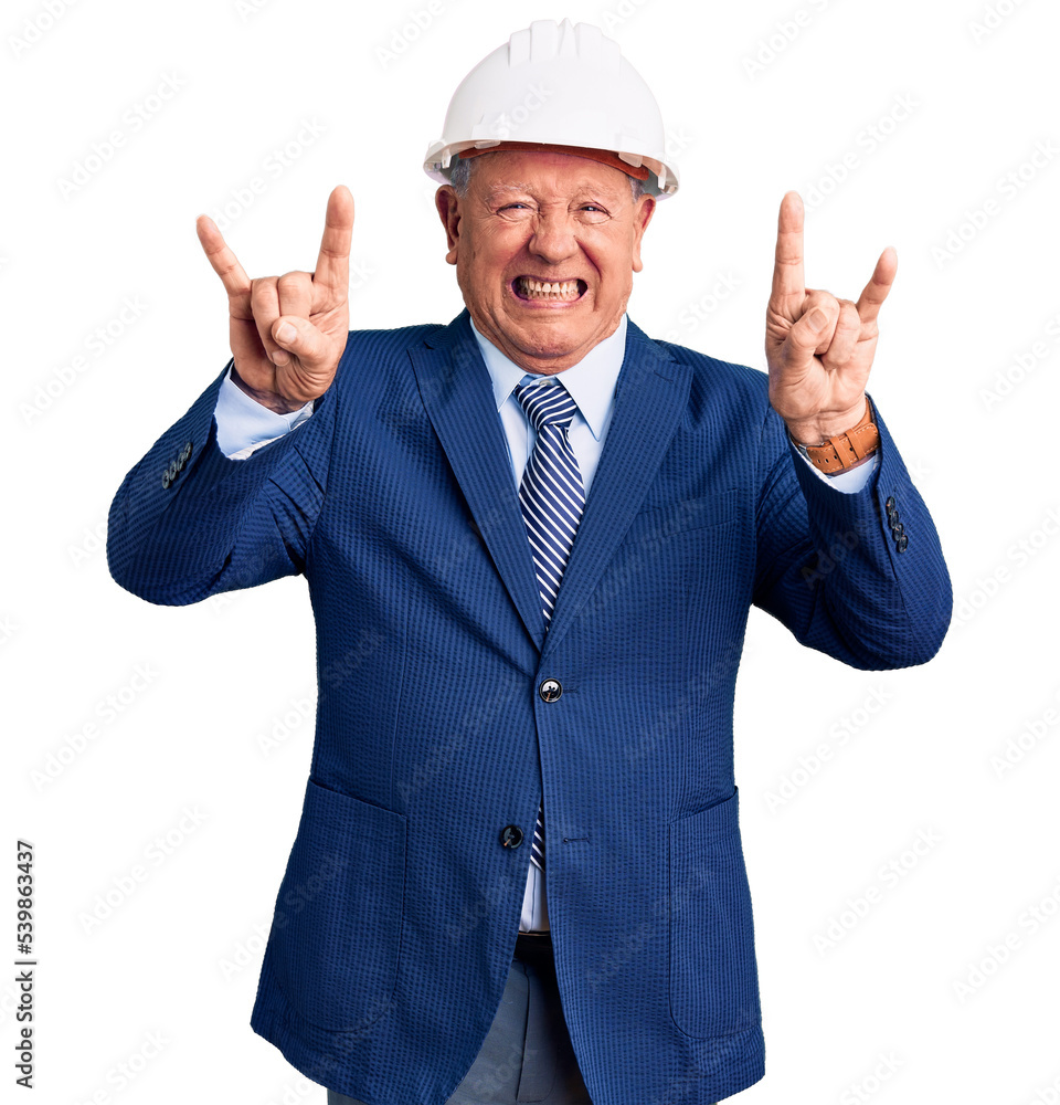 Senior handsome grey-haired man wearing suit and architect hardhat shouting with crazy expression doing rock symbol with hands up. music star. heavy concept. Senior handsome grey-haired man wearing suit and architect hardhat shouting with crazy expression doing rock symbol with hands up. music star. heavy concept.