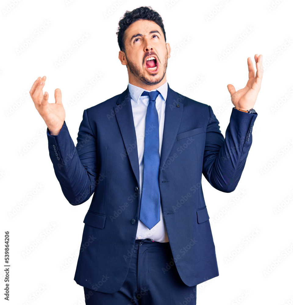 Young hispanic man wearing business clothes crazy and mad shouting and yelling with aggressive expression and arms raised. frustration concept. Young hispanic man wearing business clothes crazy and mad shouting and yelling with aggressive expression and arms raised. frustration concept.