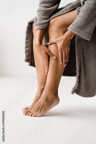 African american girl touching her legs and looking at veins. Deep vein thrombosis and varicose of woman. Sclerotherapy procedure at visiting vascular surgeon doctor. photo