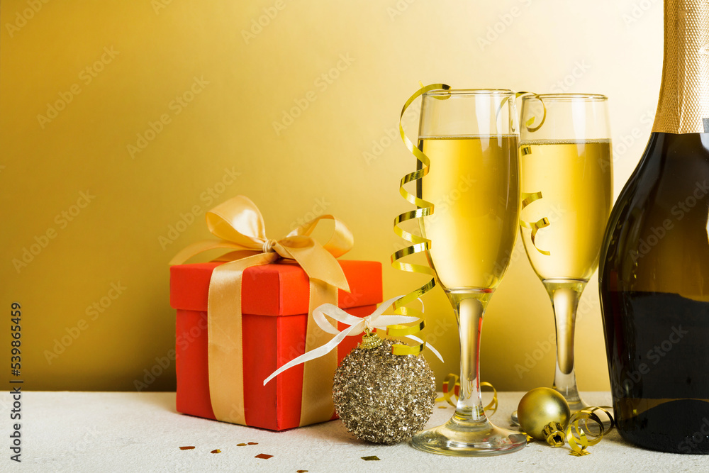 Champagne bottle with confetti, glasses and christmas decor on colored holiday background. Flat lay New Year decorations Champagne bottle with confetti, glasses and christmas decor on colored holiday background. Flat lay New Year decorations