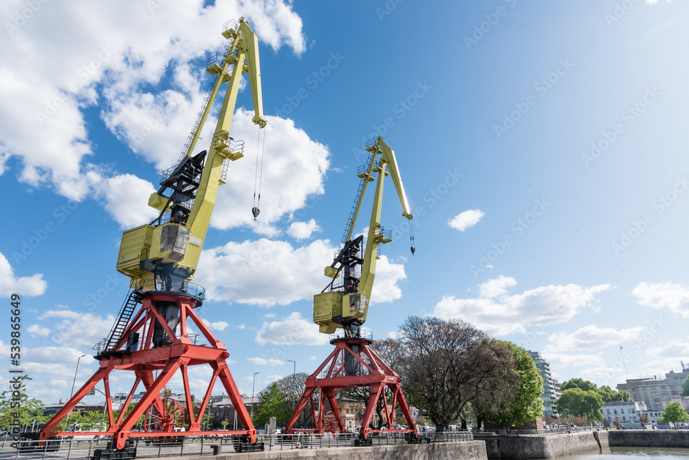 Two yellow and red port cranes with cloudy sky. Two yellow and red port cranes with cloudy sky.