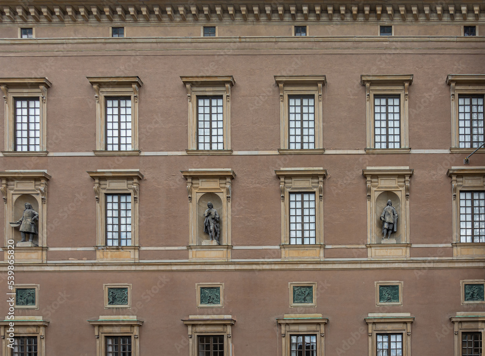 Sweden, Stockholm - July 16, 2022: Royal Palace. SW Slottsbacken facade closeup with rectangular windows and 3 male statues in niches
