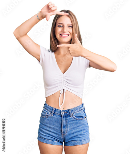 Young beautiful blonde woman wearing casual white tshirt smiling making frame with hands and fingers with happy face. creativity and photography concept.