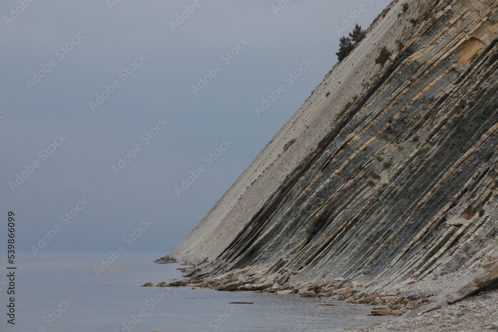 Sheer cliff in the sea with a layered texture on the surface Sheer cliff in the sea with a layered texture on the surface
