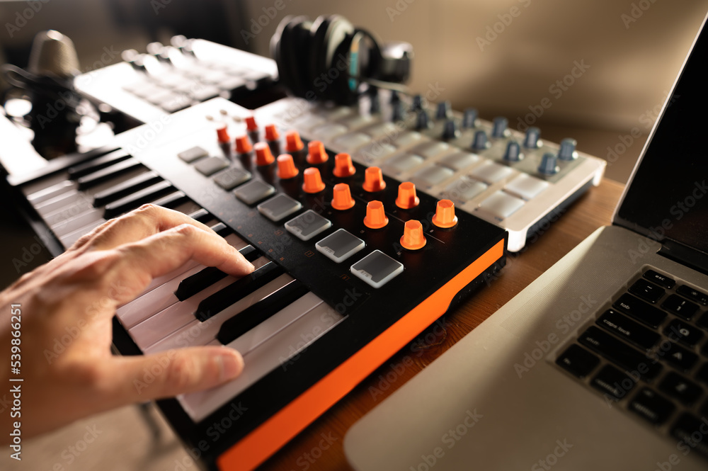 Workplace of a composer, arranger, musician, sound engineer, artist. Man's hand on midi keyboard. The working process. Sound work, podcast. Modern digital technologies. Workplace of a composer, arranger, musician, sound engineer, artist. Man's hand on midi keyboard. The working process. Sound work, podcast. Modern digital technologies.