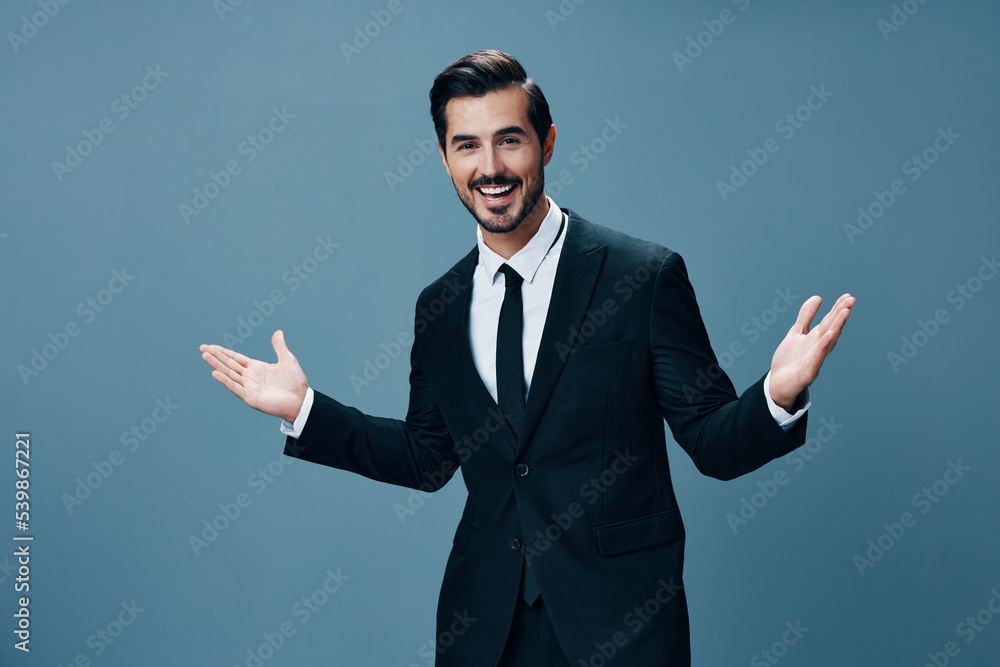Man confident businessman standing with his hands up and a smile with teeth in a stylish suit with jacket and white shirt on a gray background portrait. The concept of young businesses and startups Man confident businessman standing with his hands up and a smile with teeth in a stylish suit with jacket and white shirt on a gray background portrait. The concept of young businesses and startups