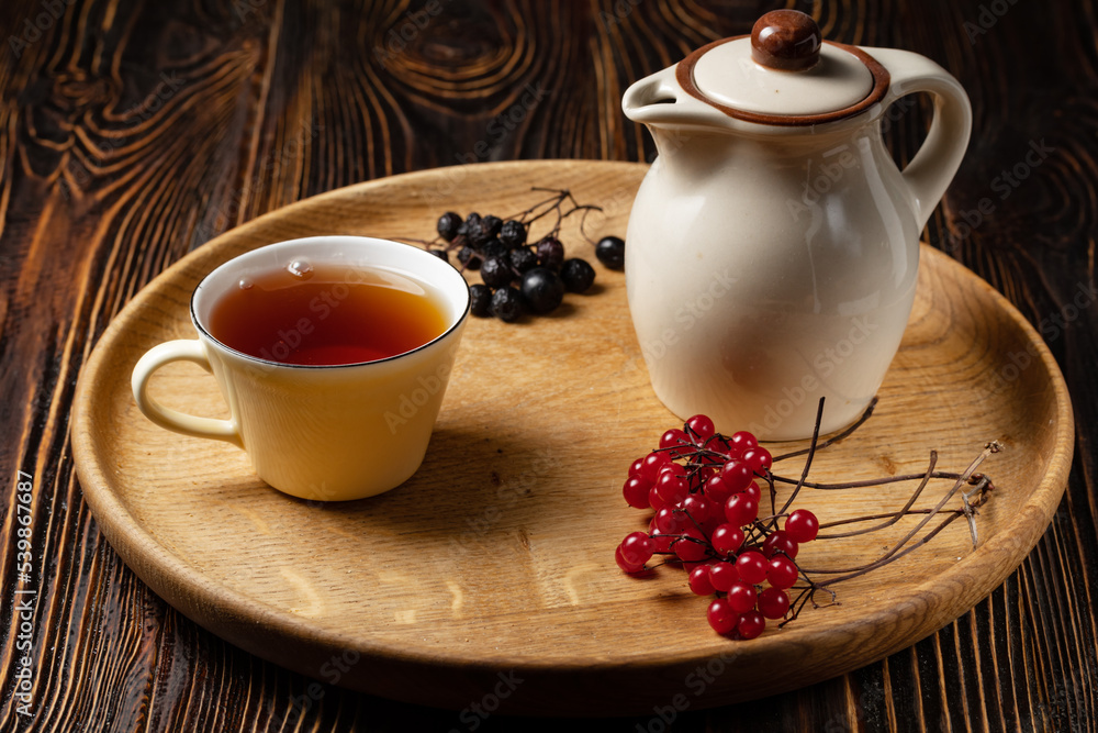cup of herbal tea and teapot on wooden table