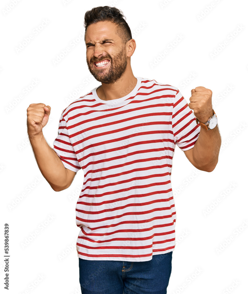Handsome man with beard wearing striped tshirt very happy and excited doing winner gesture with arms raised, smiling and screaming for success. celebration concept. Handsome man with beard wearing striped tshirt very happy and excited doing winner gesture with arms raised, smiling and screaming for success. celebration concept.