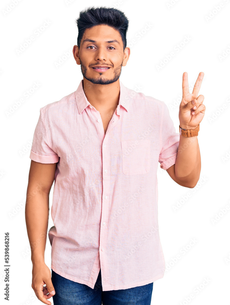 Handsome latin american young man wearing casual summer shirt smiling looking to the camera showing fingers doing victory sign. number two. Handsome latin american young man wearing casual summer shirt smiling looking to the camera showing fingers doing victory sign. number two.